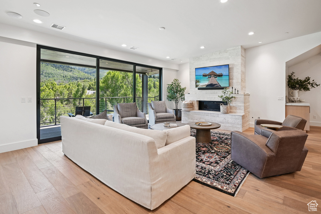 Living room featuring light wood-style floors, a fireplace, recessed lighting, and baseboards