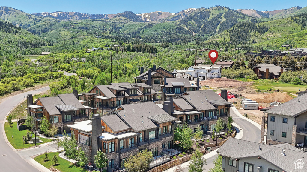 Aerial view of residential area featuring a mountainous background and a heavily wooded area