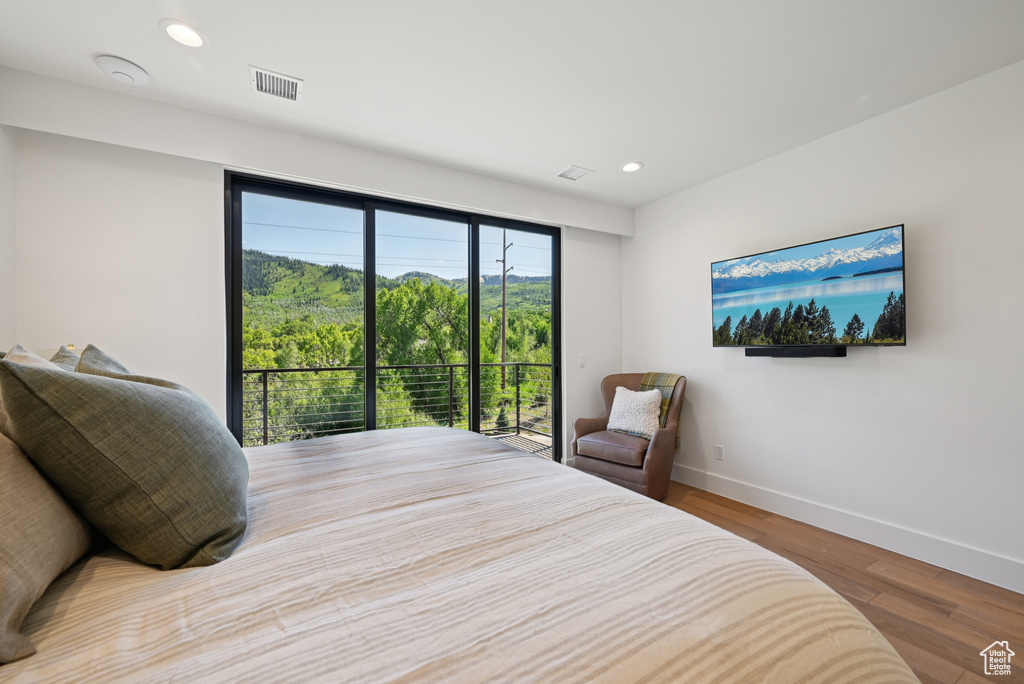 Bedroom with wood finished floors, baseboards, recessed lighting, and access to outside