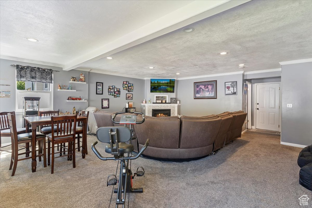 Living area with carpet flooring, recessed lighting, ornamental molding, a warm lit fireplace, and a textured ceiling