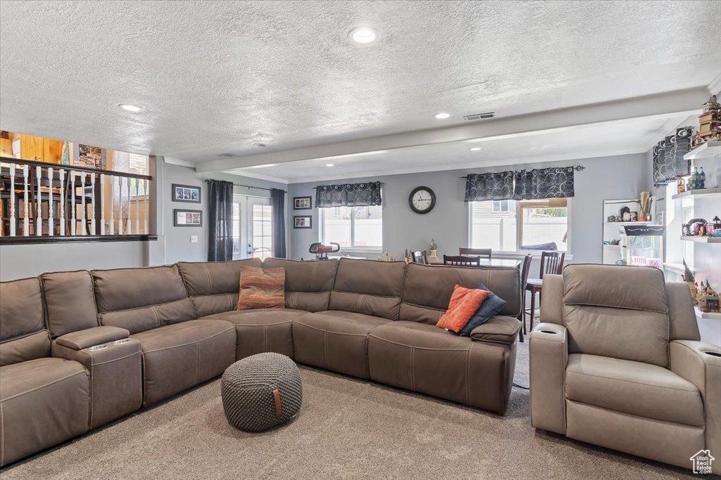 Carpeted living room with a textured ceiling, recessed lighting, and healthy amount of natural light