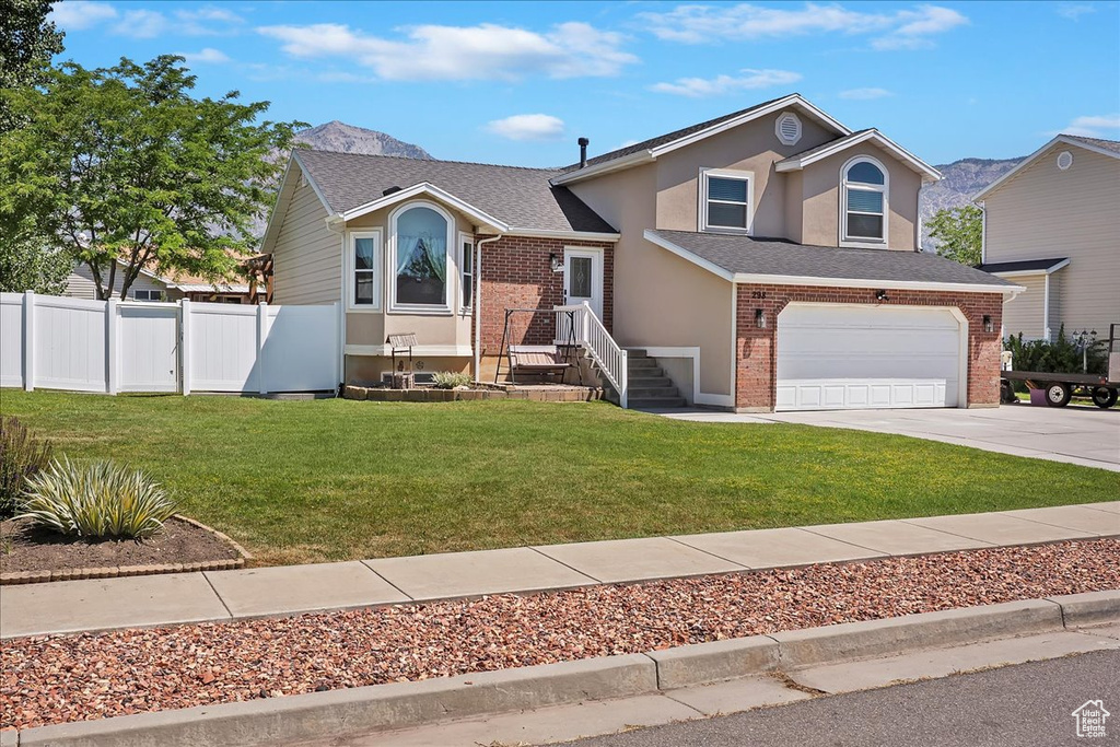 View of front of property with brick siding, concrete driveway, an attached garage, stucco siding, and a shingled roof