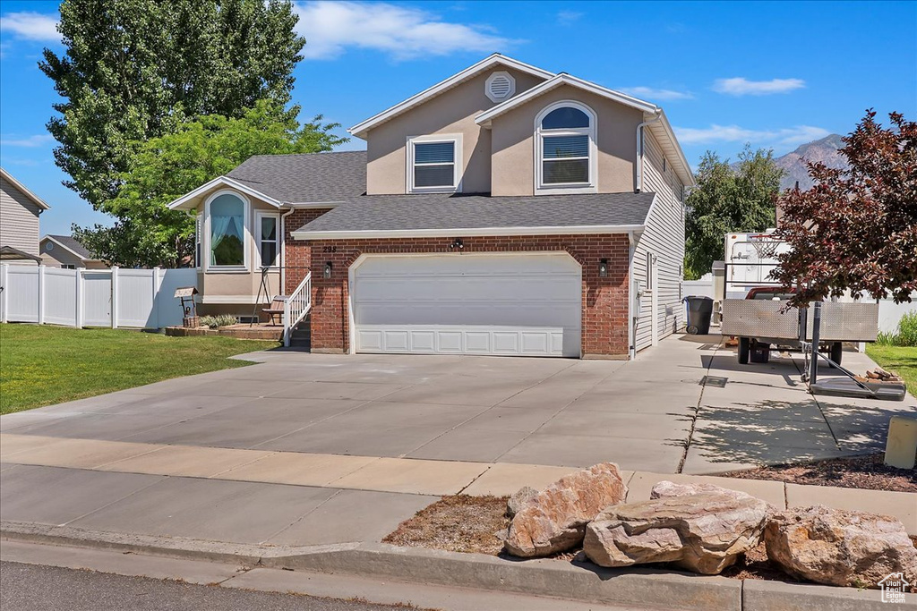 View of front of house with concrete driveway, brick siding, an attached garage, and roof with shingles