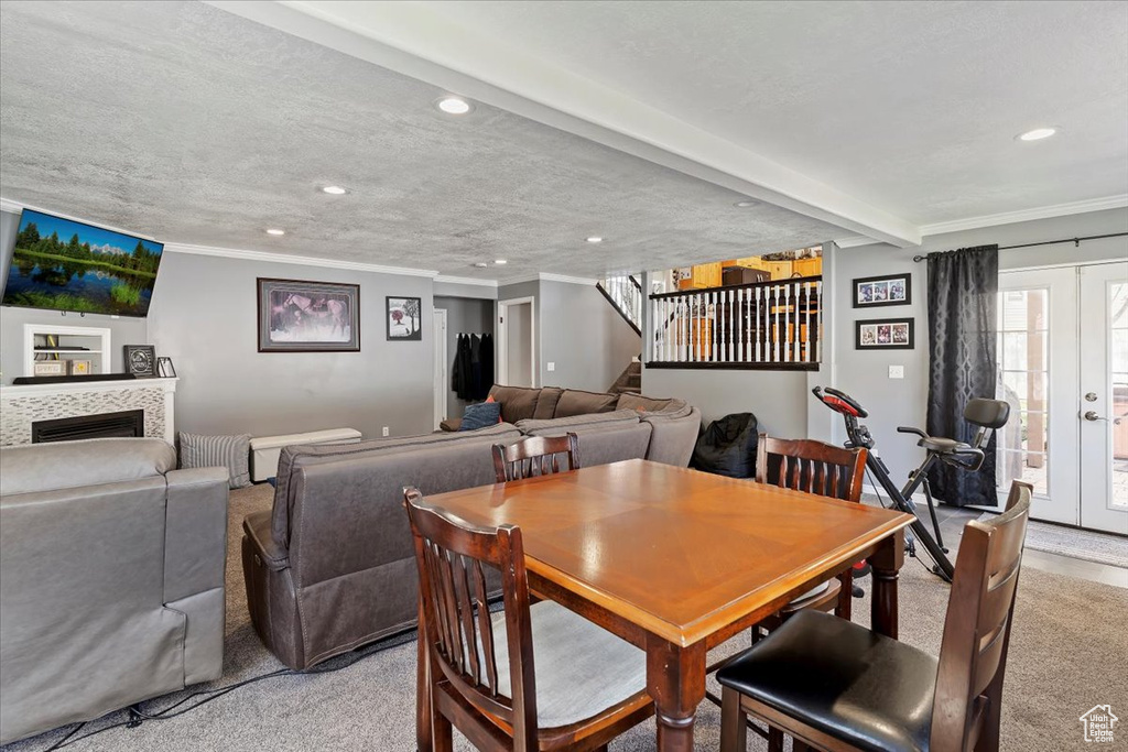 Dining room with recessed lighting, light colored carpet, ornamental molding, stairway, and a tiled fireplace