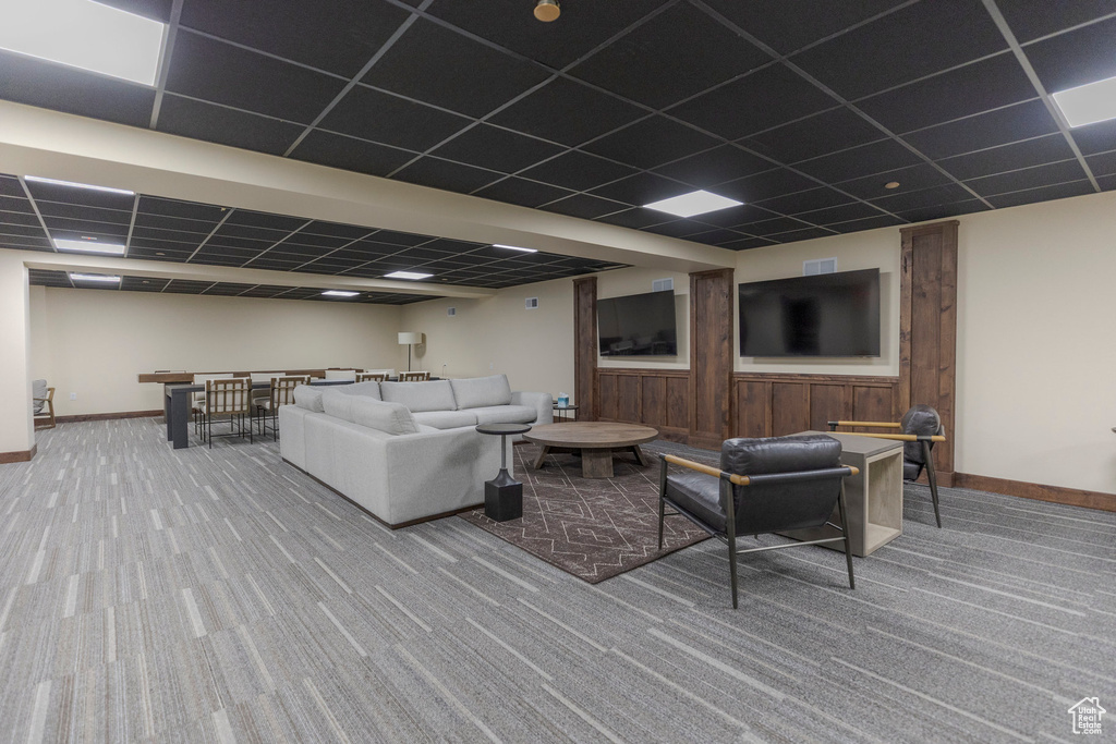 Carpeted living area with a paneled ceiling and baseboards