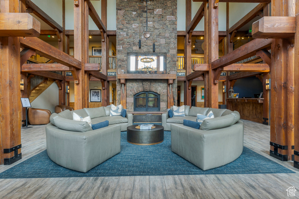 Living area featuring wood finished floors, a high ceiling, and a stone fireplace