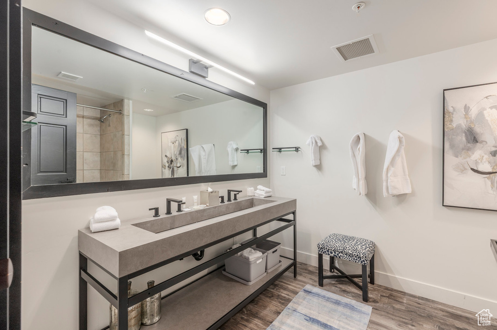 Full bathroom with wood finished floors, vanity, a shower, and baseboards
