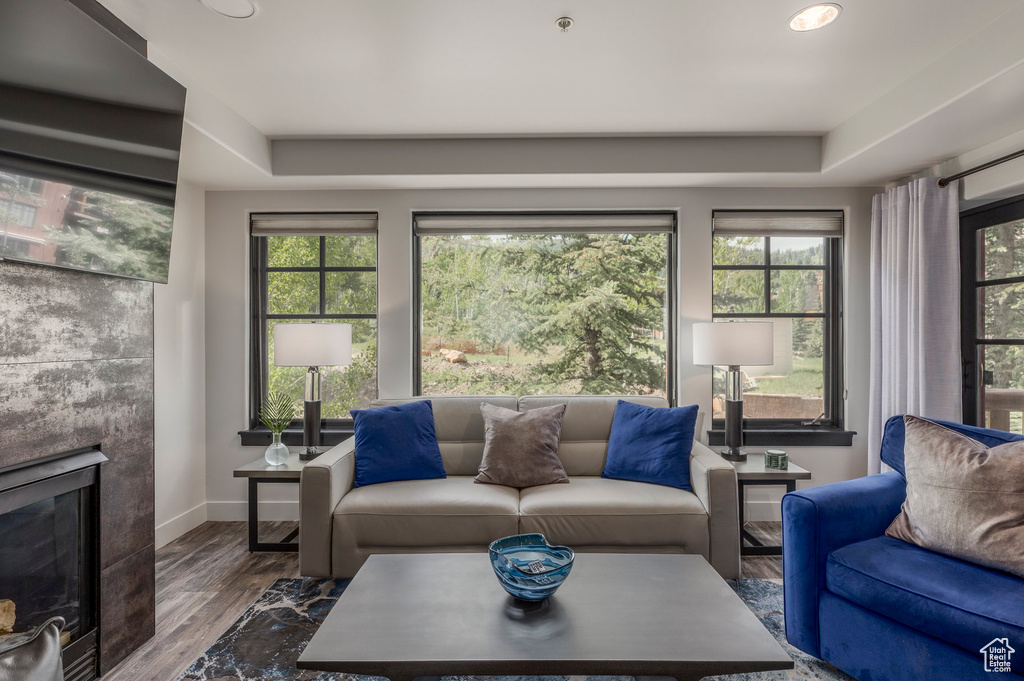 Living area with healthy amount of natural light, a tiled fireplace, wood finished floors, baseboards, and recessed lighting