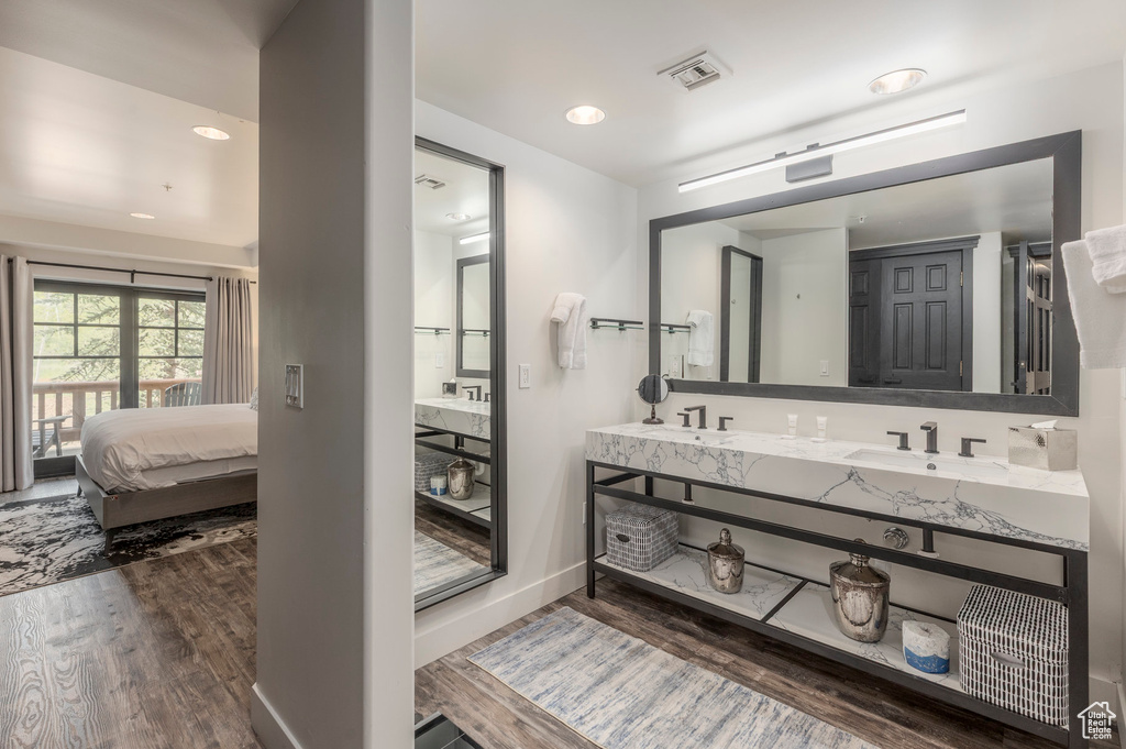 Ensuite bathroom featuring wood finished floors, double vanity, baseboards, and recessed lighting