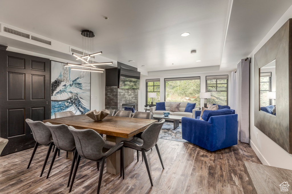 Dining area featuring wood finished floors, a tiled fireplace, a chandelier, and baseboards