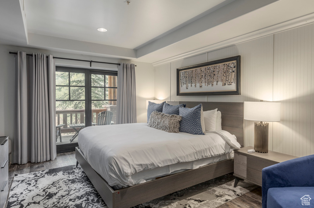 Bedroom featuring wood finished floors, access to outside, a raised ceiling, and recessed lighting