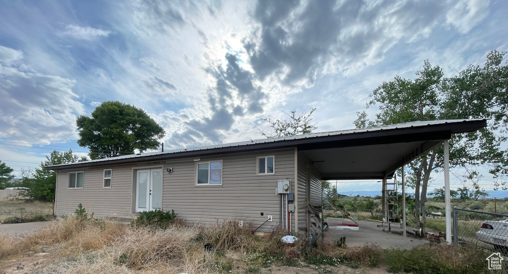 Rear view of house with an attached carport, metal roof, and a patio