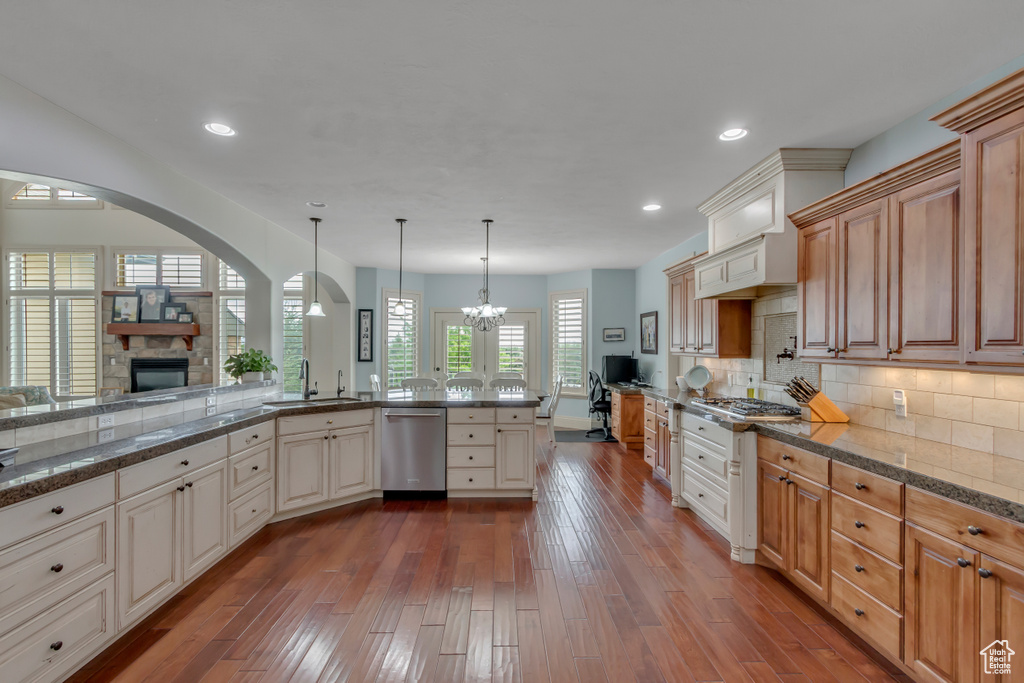 Kitchen with appliances with stainless steel finishes, a sink, a chandelier, dark wood-type flooring, and recessed lighting