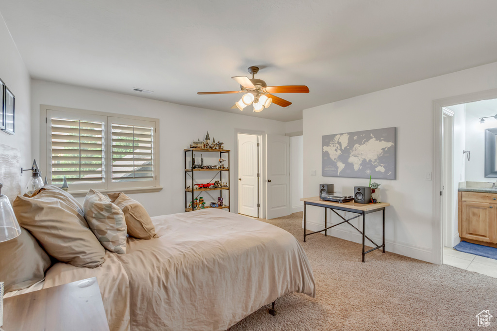 Bedroom featuring light colored carpet, ceiling fan, baseboards, and connected bathroom