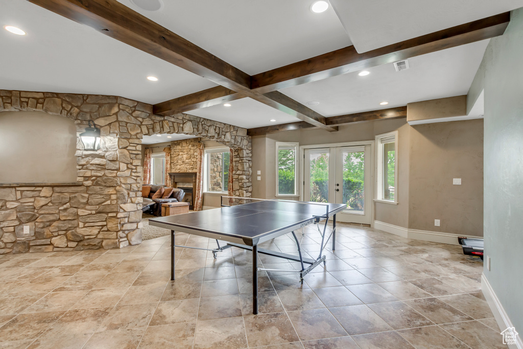 Game room with baseboards, beam ceiling, french doors, a stone fireplace, and recessed lighting