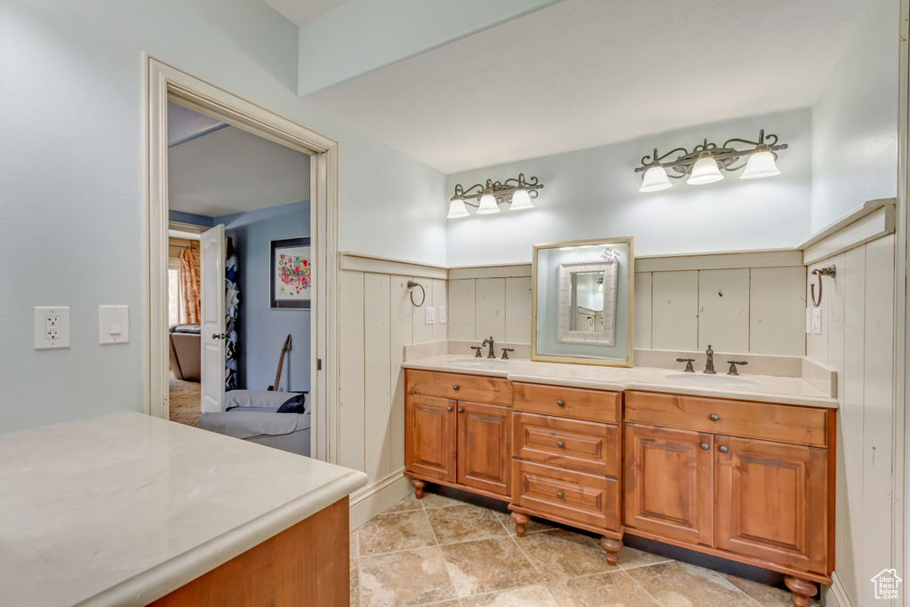 Ensuite bathroom featuring double vanity and wainscoting