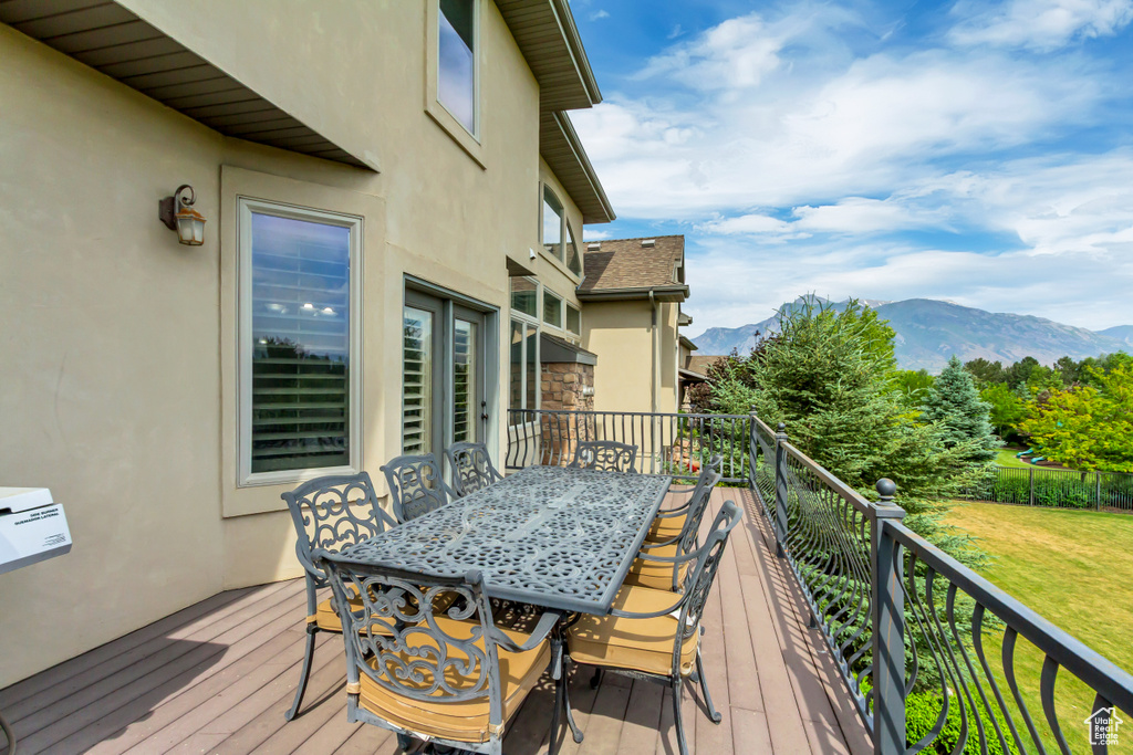 Wooden deck featuring a mountain view, a lawn, and outdoor dining area