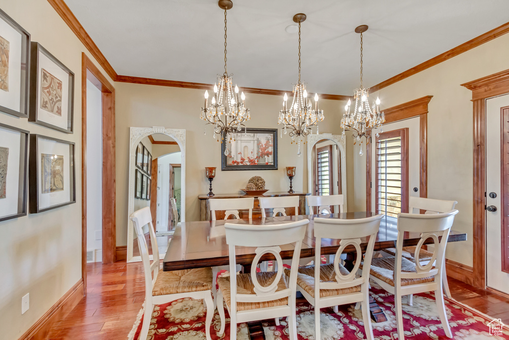 Dining room featuring a chandelier, crown molding, wood finished floors, arched walkways, and baseboards