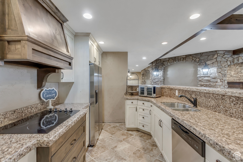 Kitchen featuring appliances with stainless steel finishes, a sink, custom exhaust hood, light stone counters, and recessed lighting