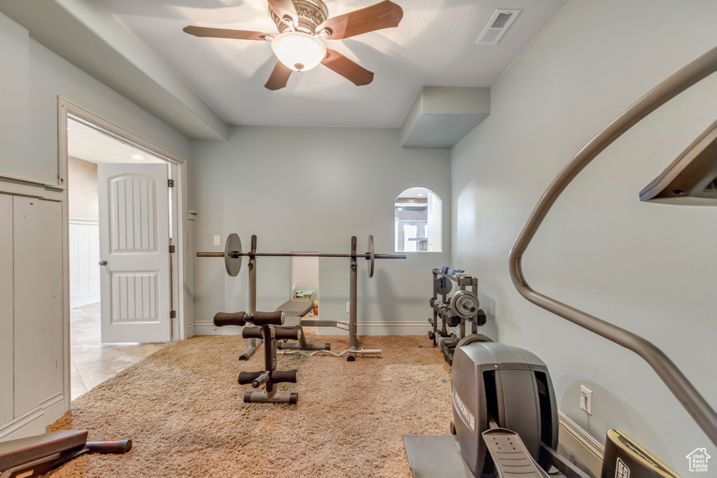 Exercise area with a ceiling fan and light tile patterned floors