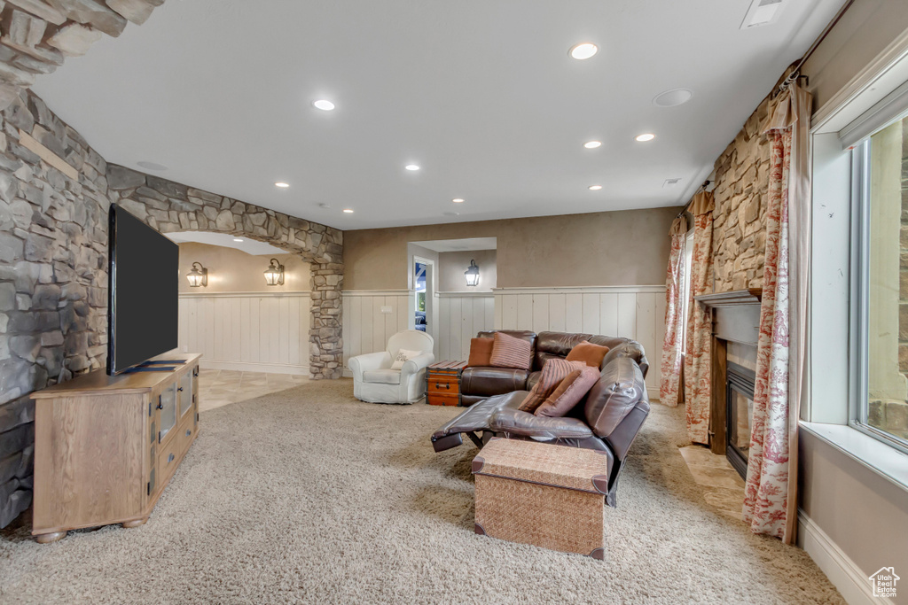 Living area featuring a wainscoted wall, light carpet, recessed lighting, a glass covered fireplace, and arched walkways
