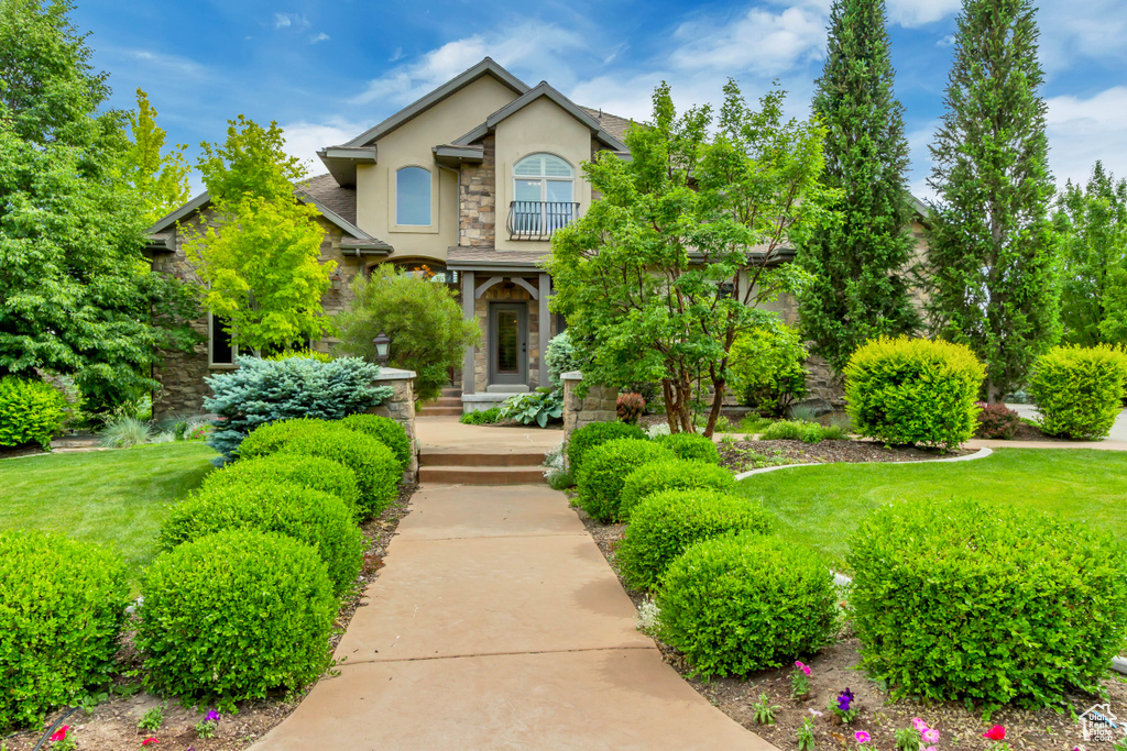 View of front of property with stone siding, stucco siding, and a front lawn