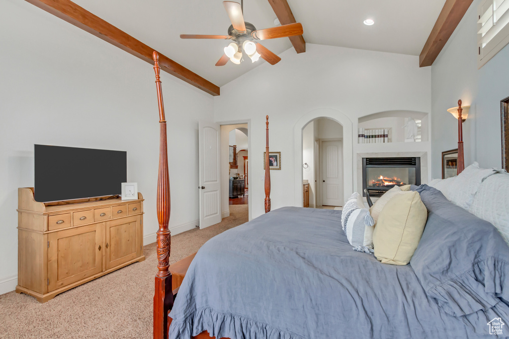 Bedroom with light carpet, a glass covered fireplace, arched walkways, a ceiling fan, and baseboards