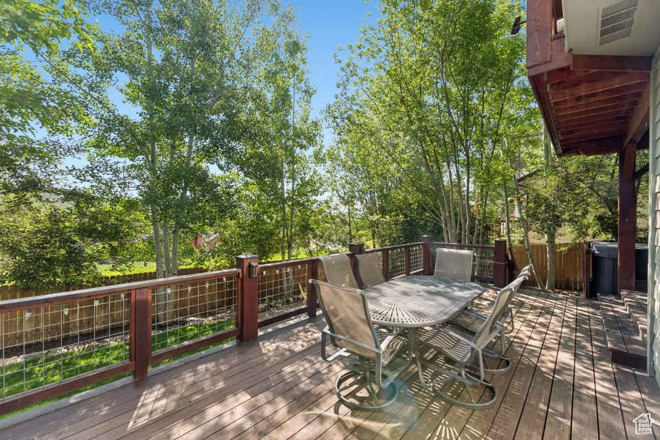 Wooden deck featuring outdoor dining area and view of wooded area