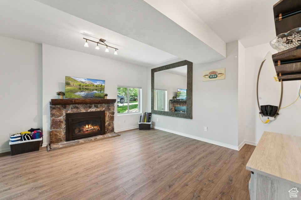 Living area featuring a stone fireplace, wood finished floors, and baseboards