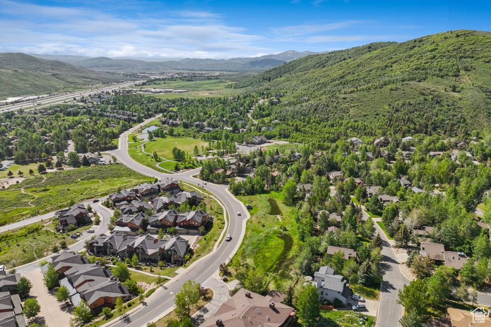 Aerial view of property and surrounding area featuring a mountainous background and nearby suburban area