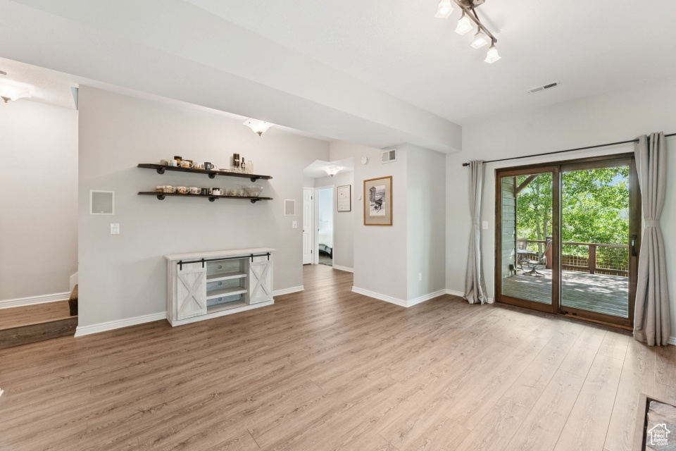 Unfurnished living room featuring light wood finished floors and baseboards