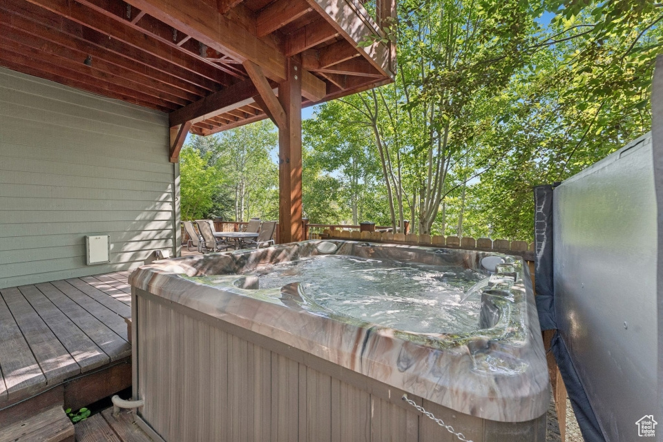 Wooden terrace with a hot tub and a fenced backyard