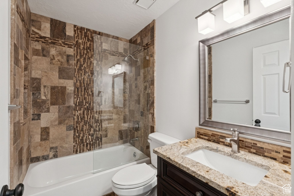 Full bath with toilet, tasteful backsplash, vanity, and shower / washtub combination