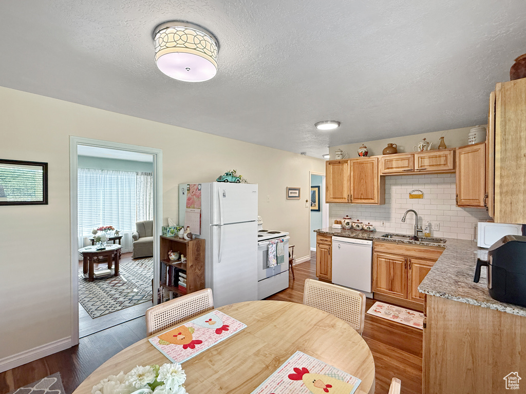 Kitchen with white appliances, backsplash, and dark wood finished floors
