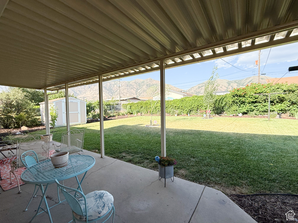 Fenced backyard featuring a shed, a patio area, and a mountain view