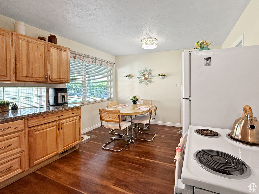 Kitchen with freestanding refrigerator, electric stove, dark wood-type flooring, and a textured ceiling