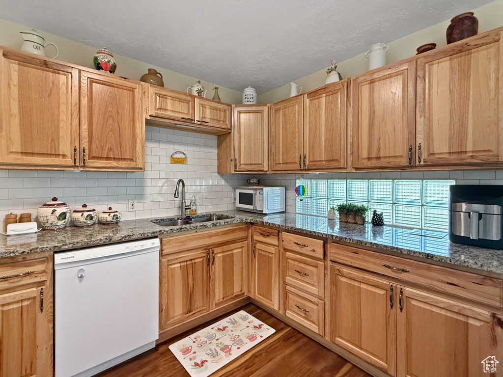 Kitchen with white appliances, dark stone counters, backsplash, dark wood finished floors, and a textured ceiling