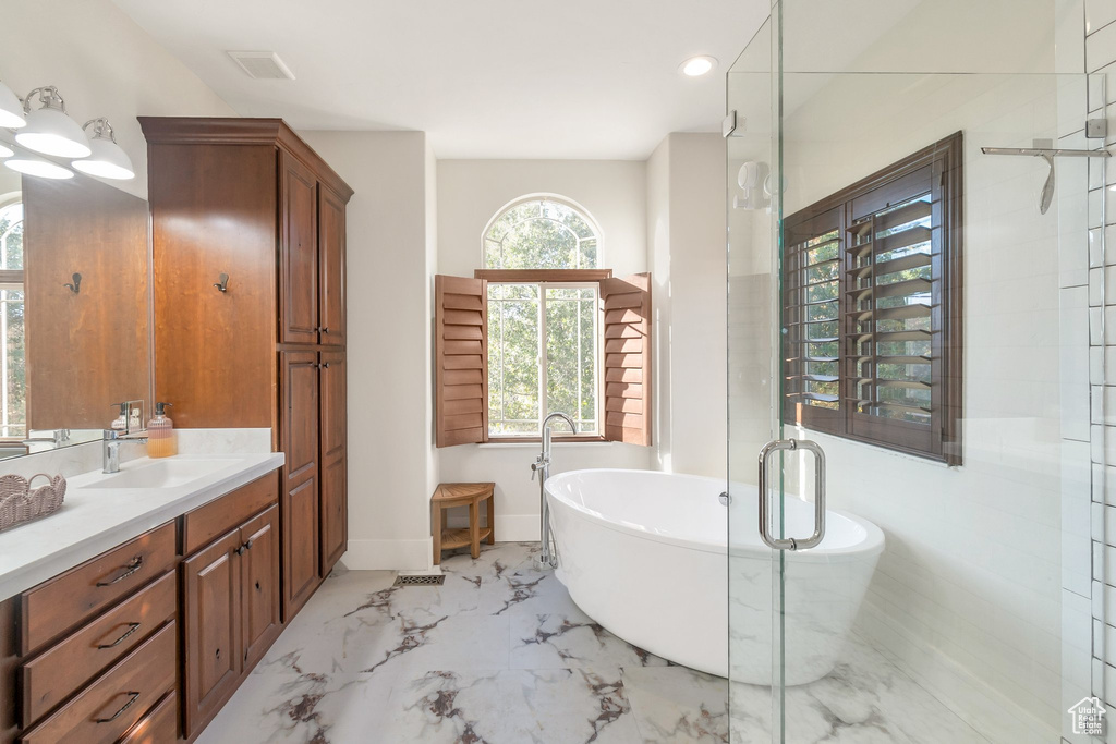 Full bath with vanity, marble tiled flooring, a freestanding tub, baseboards, and recessed lighting