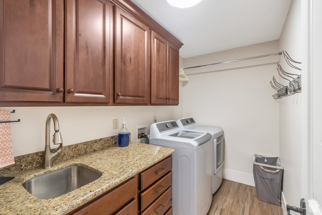 Laundry area featuring separate washer and dryer, cabinet space, light wood-style floors, and baseboards