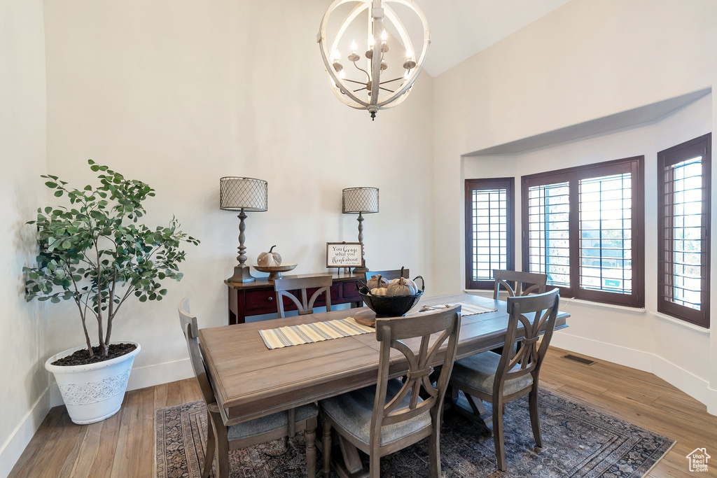 Dining area with baseboards, a chandelier, wood finished floors, and a towering ceiling