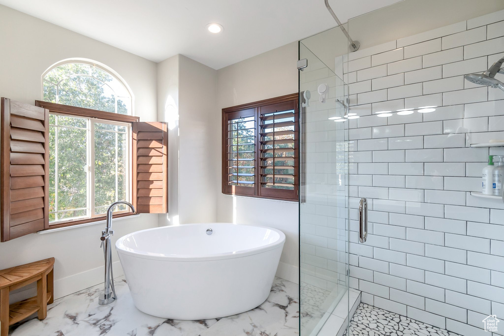 Bathroom featuring marble look tile flooring, a shower stall, a freestanding tub, recessed lighting, and baseboards