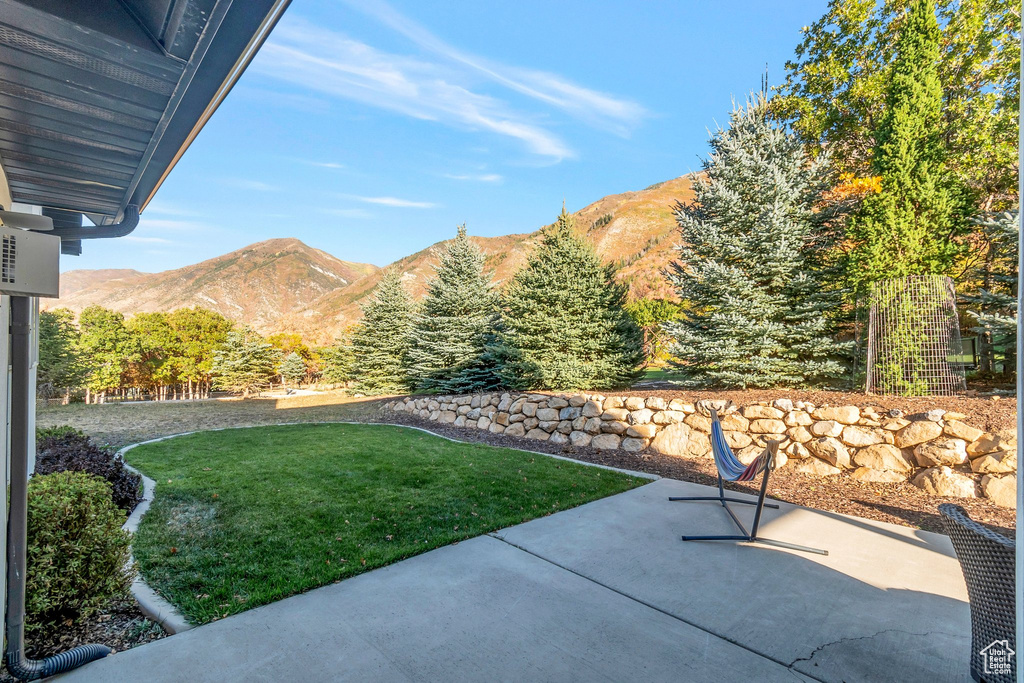 View of grassy yard with a mountain view and a patio area