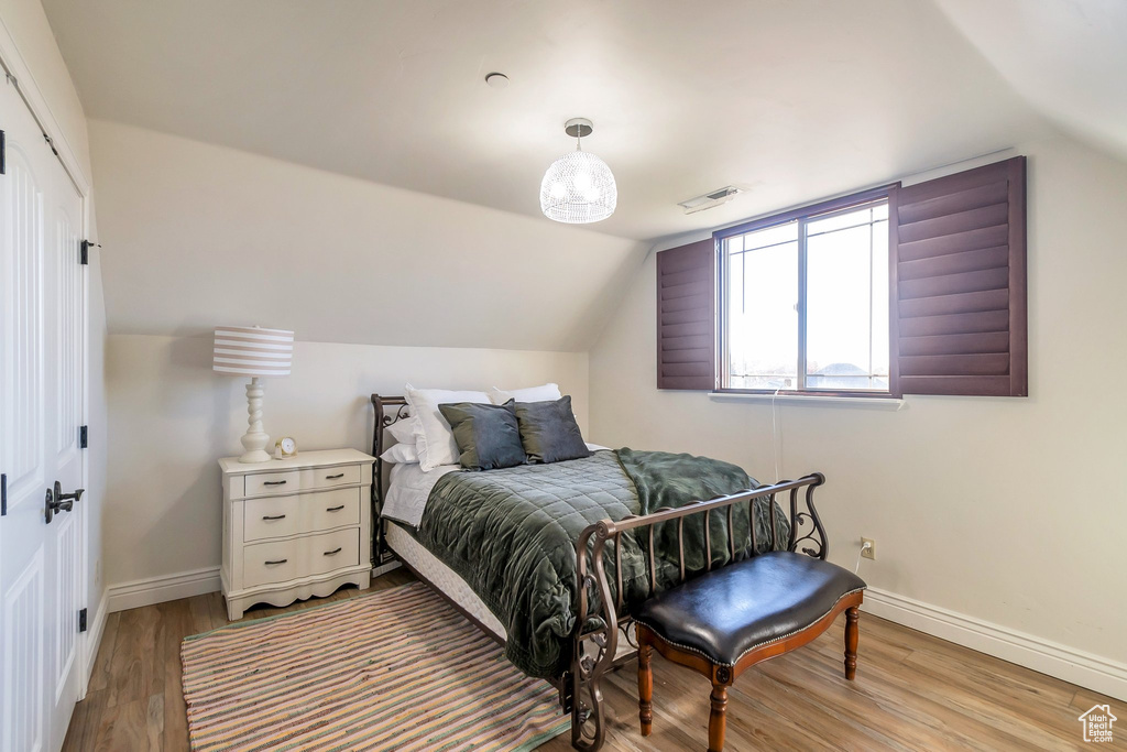 Bedroom featuring light wood-type flooring, baseboards, vaulted ceiling, and a closet