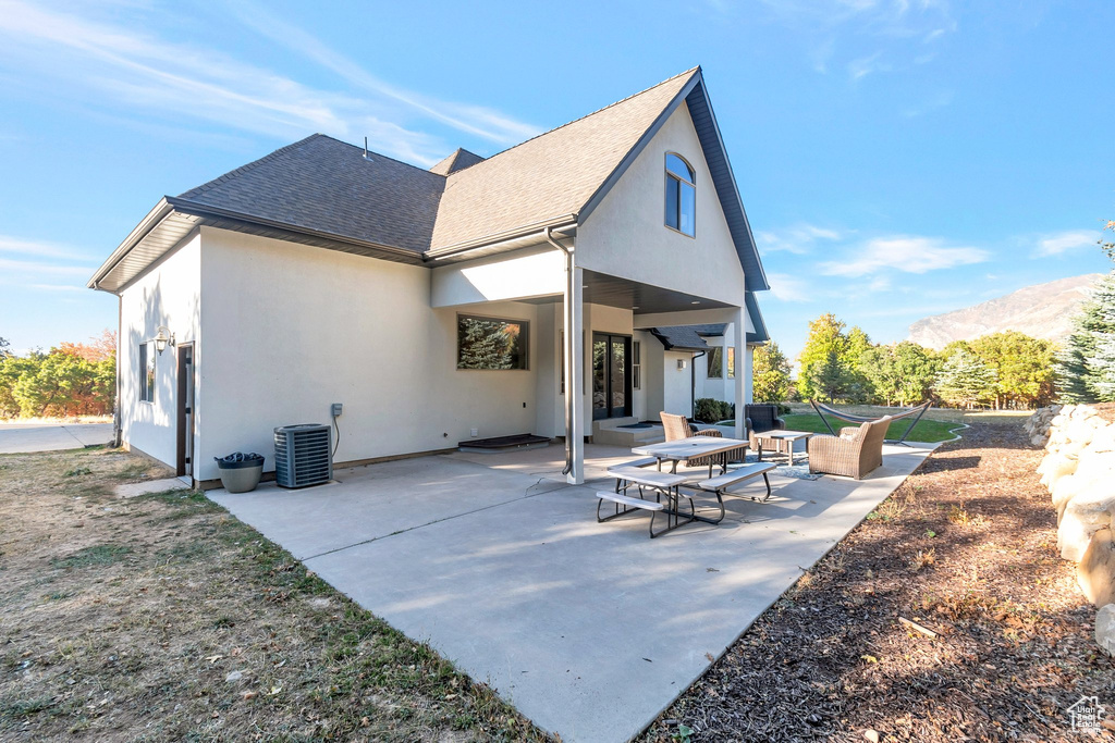 Back of property featuring roof with shingles, stucco siding, a patio, and a mountain view