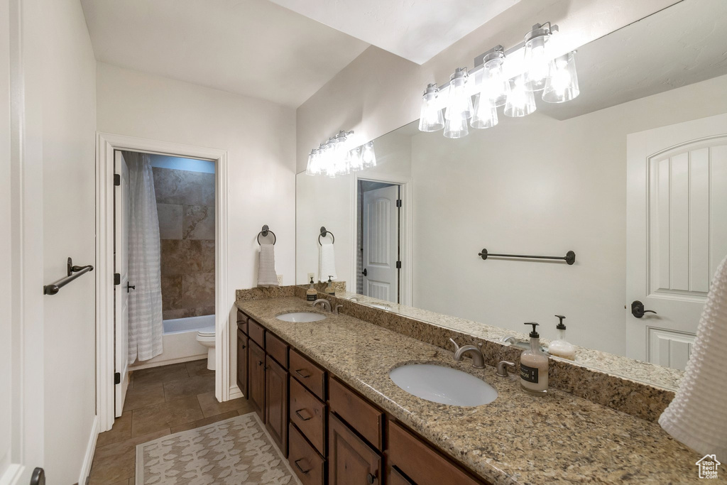 Bathroom with double vanity, toilet, and shower / bath combination with curtain