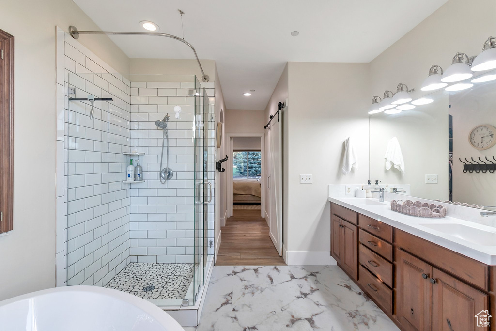 Bathroom with a shower stall, double vanity, marble look tile flooring, a soaking tub, and connected bathroom