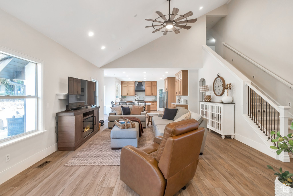 Living room featuring ceiling fan, light wood-style floors, high vaulted ceiling, baseboards, and recessed lighting
