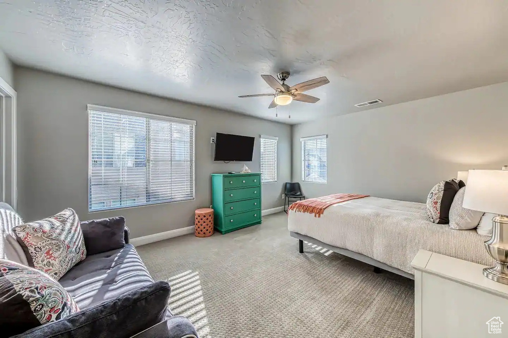 Bedroom with baseboards, light colored carpet, and ceiling fan