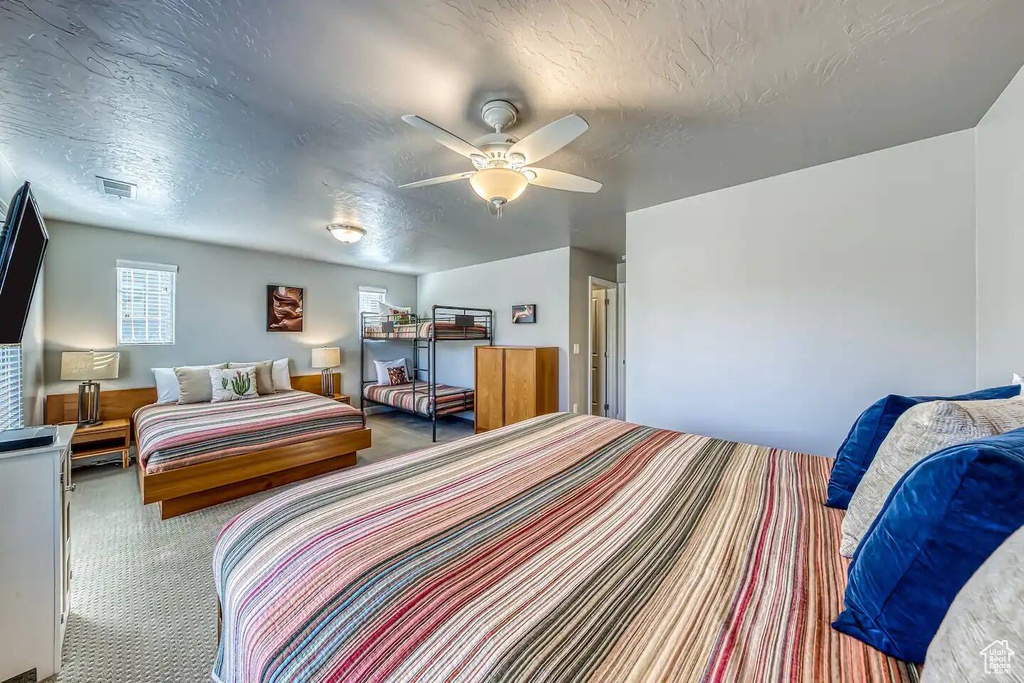 Carpeted bedroom with a textured ceiling and ceiling fan