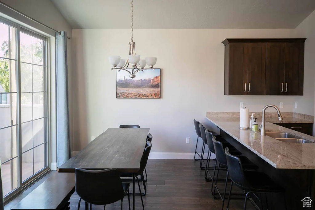 Dining room featuring dark wood-style floors, a chandelier, and baseboards